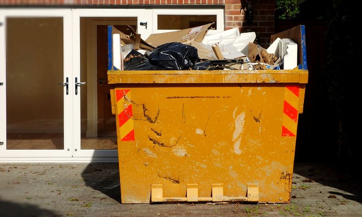 Dónde tirar muebles viejos en Salamanca Contenedor de obra lleno de muebles y enseres frente a la puerta de una vivienda