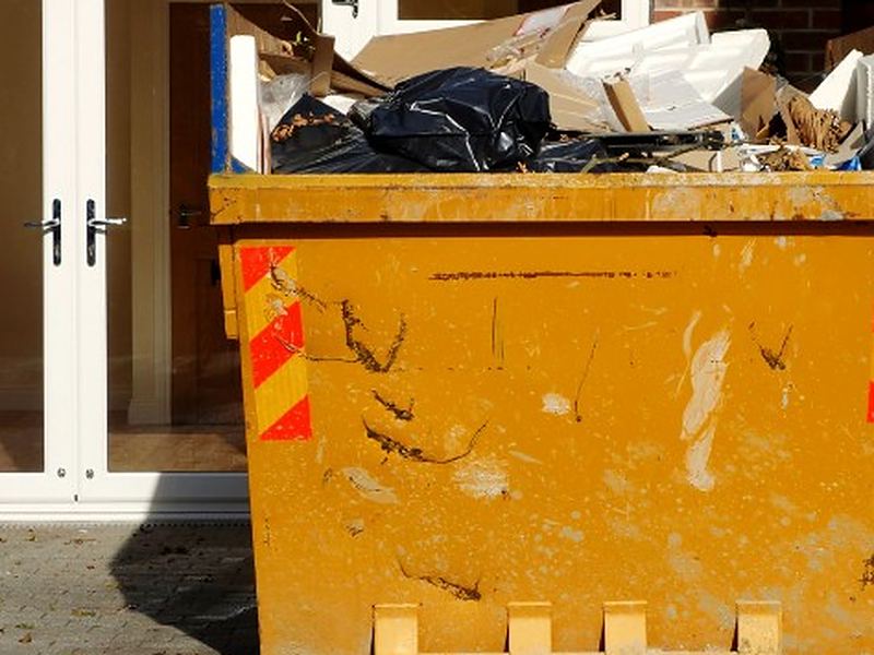 Volumen real de un vaciado doméstico Contenedor lleno de muebles y enseres frente al portal de una vivienda